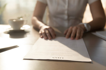 Woman sitting at the desk with loan agreement form. Close up photo of female hands lying on...
