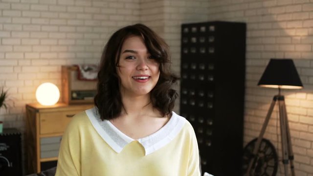 portrait of young cute and enamored woman with dark hair smile flirty and glancing with shy to the camera
