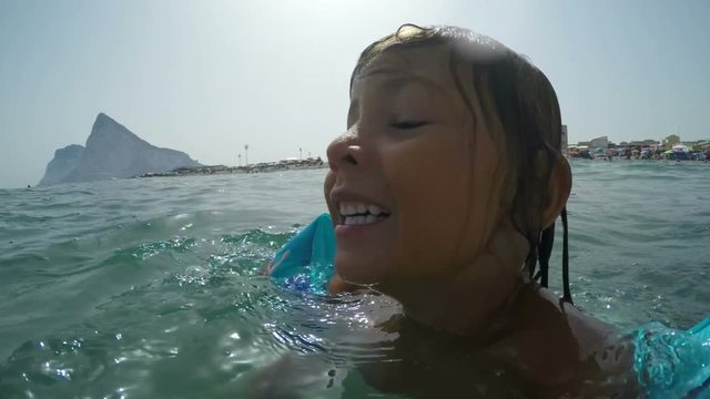 Close-up of happy girl with inflatable armbands enjoying sea and summer vacation in Andalusia, Spain.