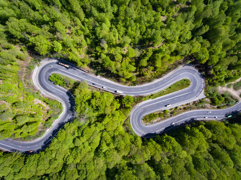 Curved road in the forest. Transylvania, Romania, Europe. Cars passing on road.