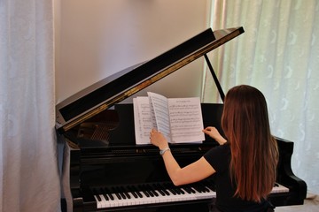 Girl choosing a song to play on her piano