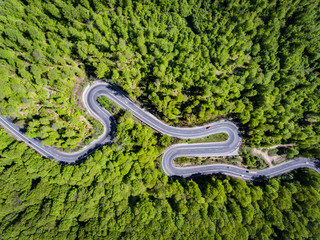 Winding road in the forest. Transylvania, Romania, Europe. Cars passing on road.