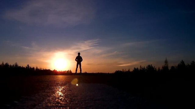 Silhouette of a young guy on a segway ride from the sunset.