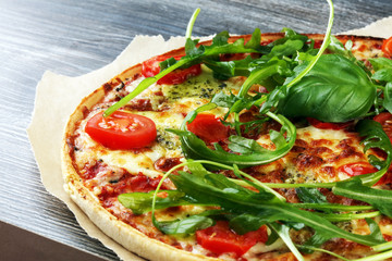 Hot true ITALIAN PIZZA with basil, arugula and cheese. TOP VIEW Tasty traditional pepperoni pizza on board on wooden table with decoration