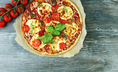 Hot true ITALIAN PIZZA with basil and cheese. TOP VIEW Tasty traditional pepperoni pizza on board on wooden table with decoration