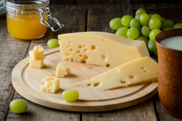 Cheese with honey and grapes on a wooden table
