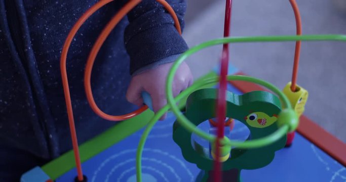 toddler plays with bead roller coster toy - close up on hands