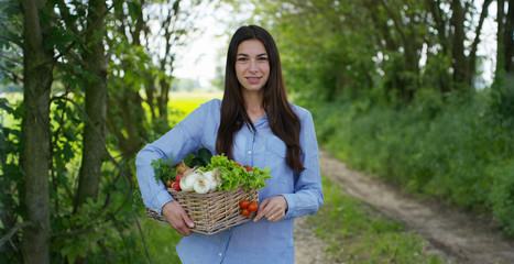 Beautiful young girl holding a basket of vegetables, in the background of nature. Concept: biology, bio products, bio ecology, grow vegetables, natural pure and fresh product, vegetarians, healthy.