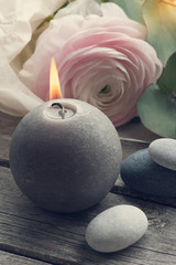 Pink ranunculus, pebbles and lit candle