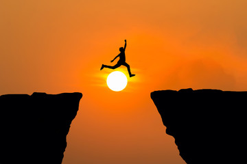 Man jumping over cliff on sunset background,Business concept idea