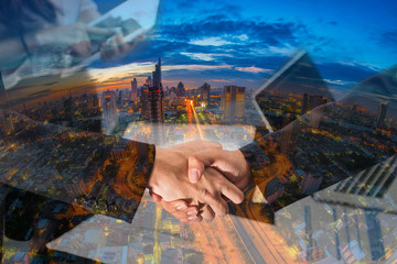 Double Exposure of a businessman handshake on Aerial view of cityscape Bangkok business district at twilight  background.