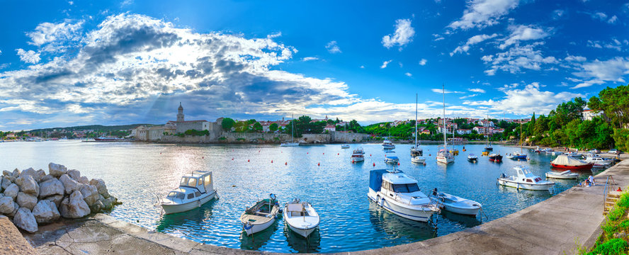 Wonderful romantic summer evening landscape panorama coastline Adriatic sea. Boats and yachts in harbor at cristal clear azure water. Old town of Krk on the island of Krk. Croatia. Europe.