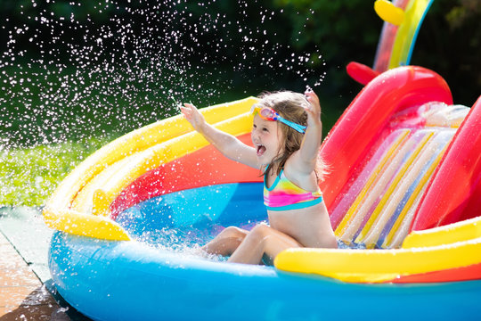 Child In Garden Swimming Pool With Slide