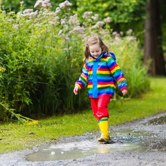 Kids play in rain and puddle in autumn