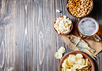Fototapeta na wymiar Lager beer glasses and snacks on wooden table. Nuts and dry fish. With copy space