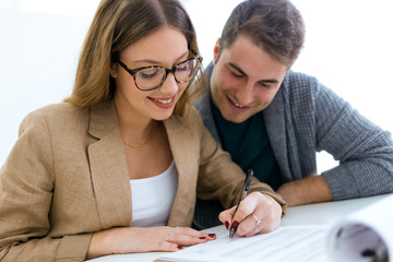 Fototapeta premium Beautiful young couple signing financial contract in the office.