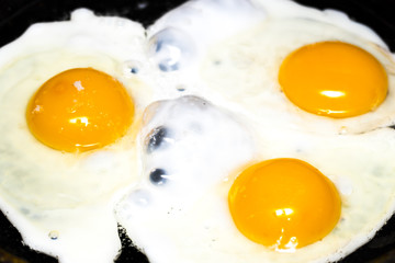 Fried eggs in a frying pan  for breakfast on a black background
