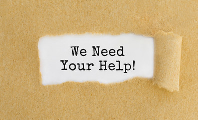 Text We Need Your Help appearing behind ripped brown paper