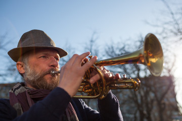 An elderly musician plays in the street on a trumpet in spring day © Viktor Koldunov