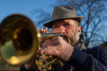 Obraz premium An elderly musician plays in the street on a trumpet in spring day