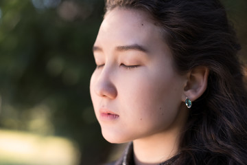Portrait of a beautiful asian girl with closed eyes. She dreams about something