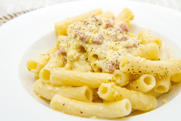 white dish with penne and carbonara sauce