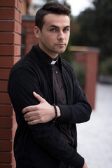 Portrait of handsome catholic bearded priest or pastor posing outdoors.