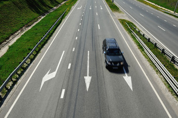 The car is driving on the highway in a sunny day