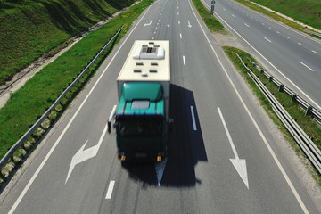 The truck is driving along the highway in a sunny day