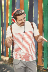 Handsome man with headphones listening music on colorful background