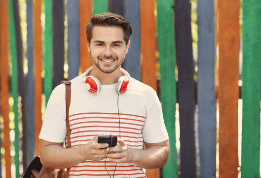 Handsome man with headphones listening music on colorful background