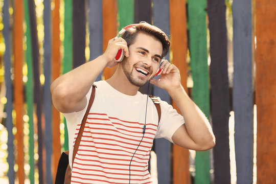 Handsome man with headphones listening music on colorful background