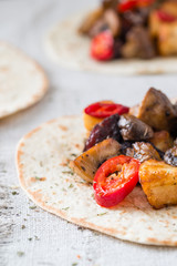 Closeup of tacos with grilled mushrooms, Spanish spicy sausage chorizo, Mexican tortillas, Cypriot cheese halloumi, hot chilly and dried oregano on cloth background