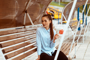 Tinted portrait of a young girl in a shirt sitting on a wooden bench