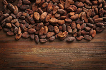 Aromatic cocoa beans on wooden background
