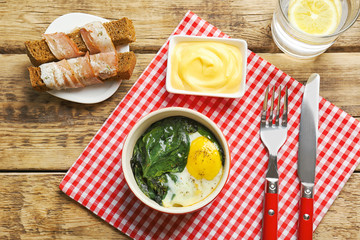 Delicious eggs Florentine in bowl and napkin on wooden table