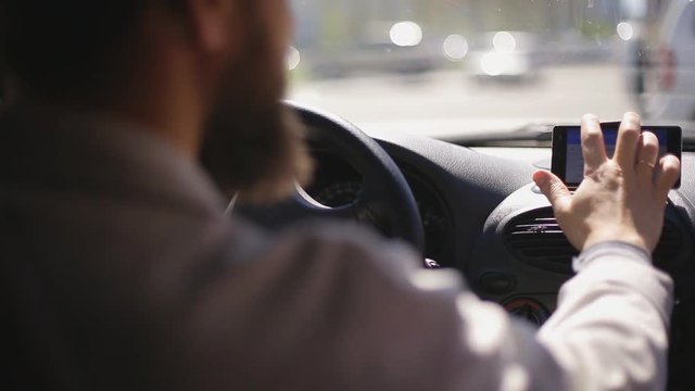 A man gets into the car and turns on the navigator on the smartphone