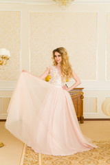 Fototapeta premium Portrait of beautiful young bride. A girl is posing in a hotel room. The lady is spinning in her wedding dress