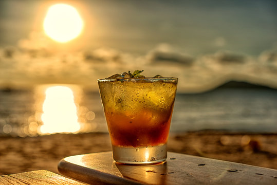 The frozen glass of Mojito drinks on the beach at sunset with blur background.