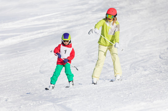 Little boy training skiing with female instructor