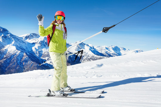 Girl on button ski lift going uphill, waving hand