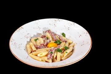 Pasta Carbonara with bacon and raw egg yolk on the plate.