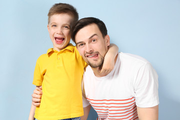Handsome man and his son on color background