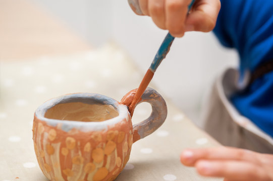 The boy is painting the cup. A cup closeup