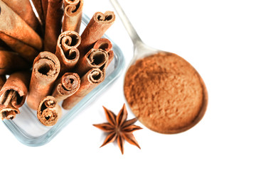 Cinnamon powder and sticks in bowl with anise star isolated on white, top view