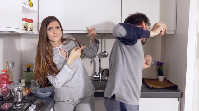 cute funny woman pushing away boyfriend dancing in kitchen