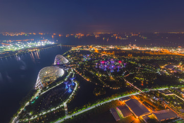 Naklejka premium Aerial view of Gardens by the bay by night, a nature park in central Singapore, part of a strategy by the Singapore government to transform Singapore from a Garden City to a City in a Garden.