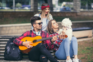 Obraz na płótnie Canvas Friends in the park having fun, playing guitar