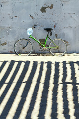 Fototapeta na wymiar Green Bicycle on the sand at the old wall.