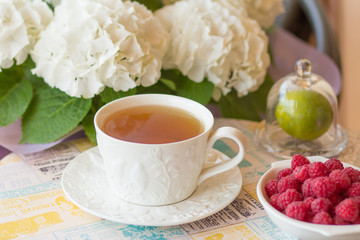 A festive morning breakfast, tea with croissants, muffins and raspberries on a background of white flowers